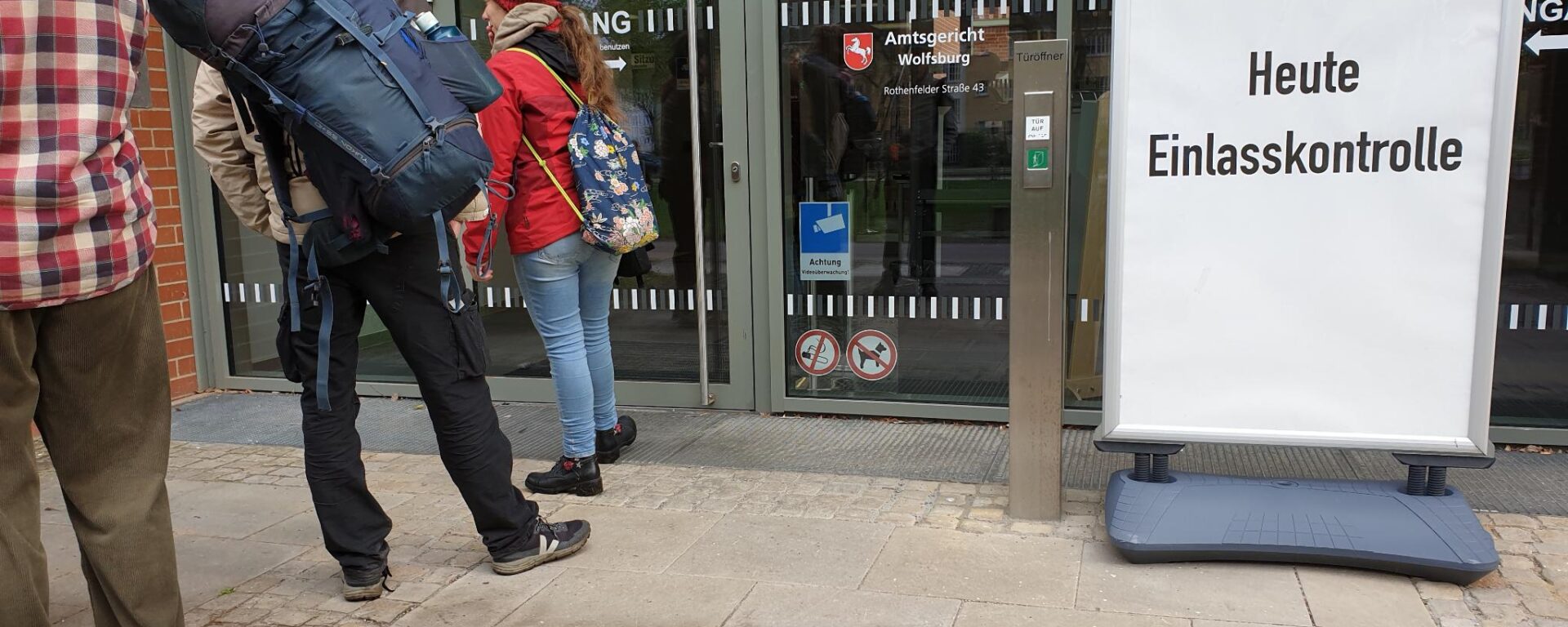 Schlange vor dem Gerichtsgebäude sowie ein Aufstelllschild "Heute Einlasskontrolle"